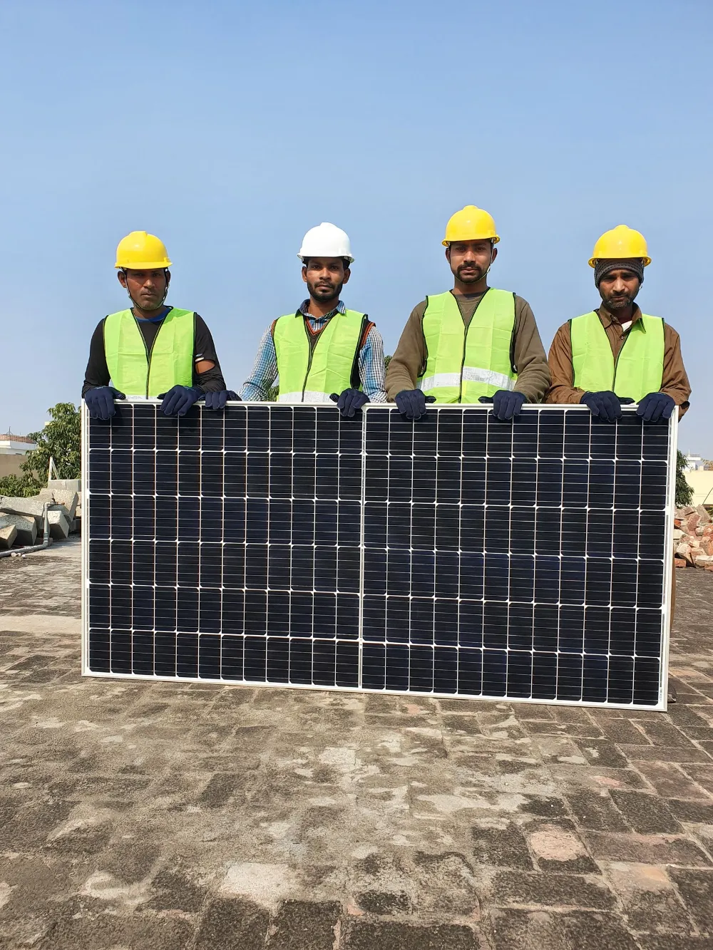 Sadguru Solar installation team holding a solar panel on a rooftop